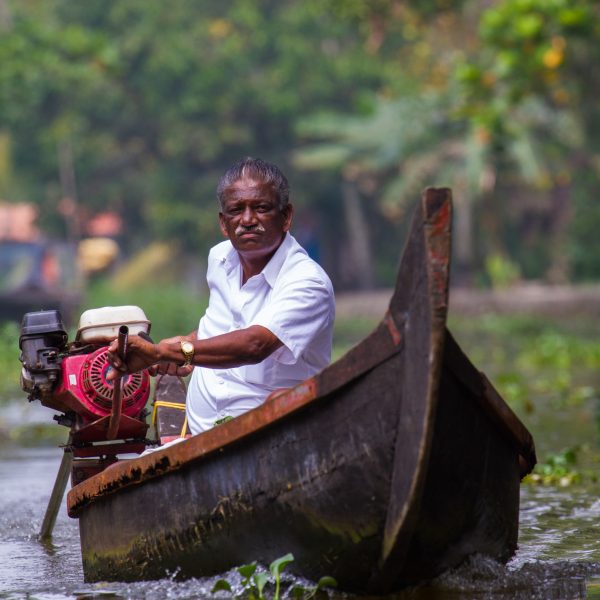 A man navigates the rivers of Kerala's backwaters in a small boat