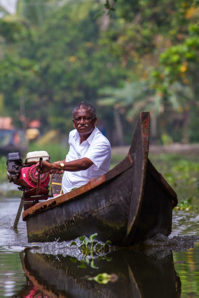 A man navigates the rivers of Kerala's backwaters in a small boat